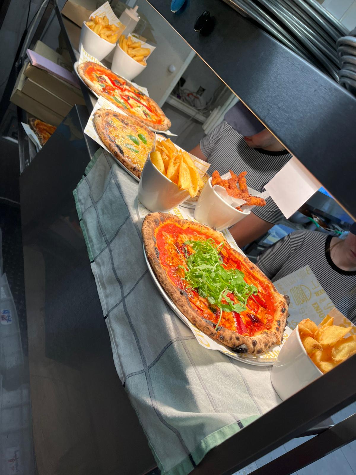 Fresh pizzas and sides lined up on the pass at Luso restaurant