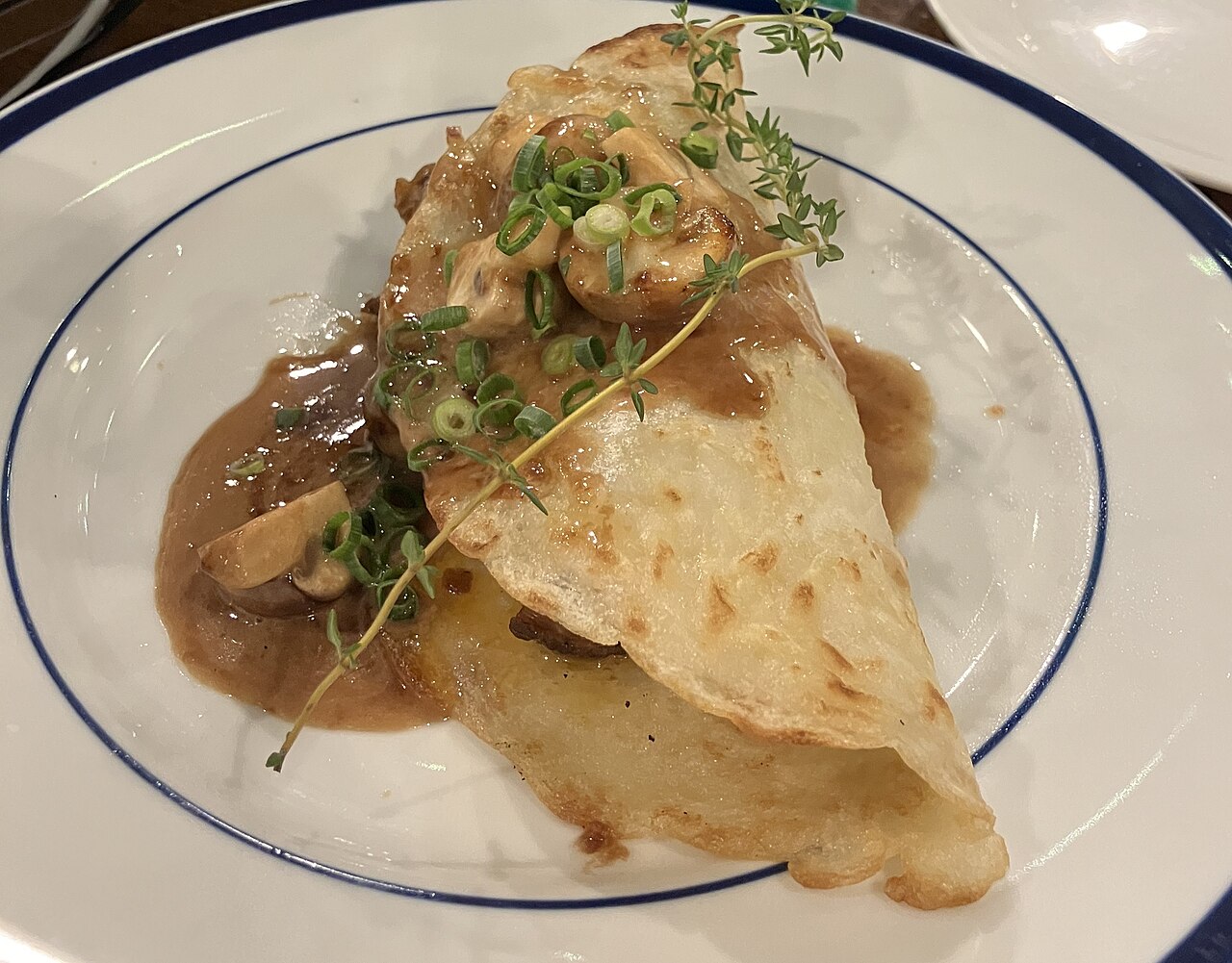 A folded boxty pancake filled with meat in a creamy mushroom sauce