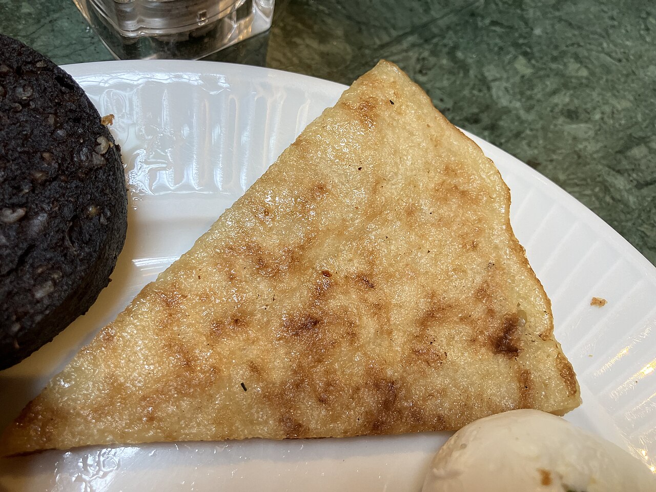 A triangle of griddled boxty potato bread served with black pudding